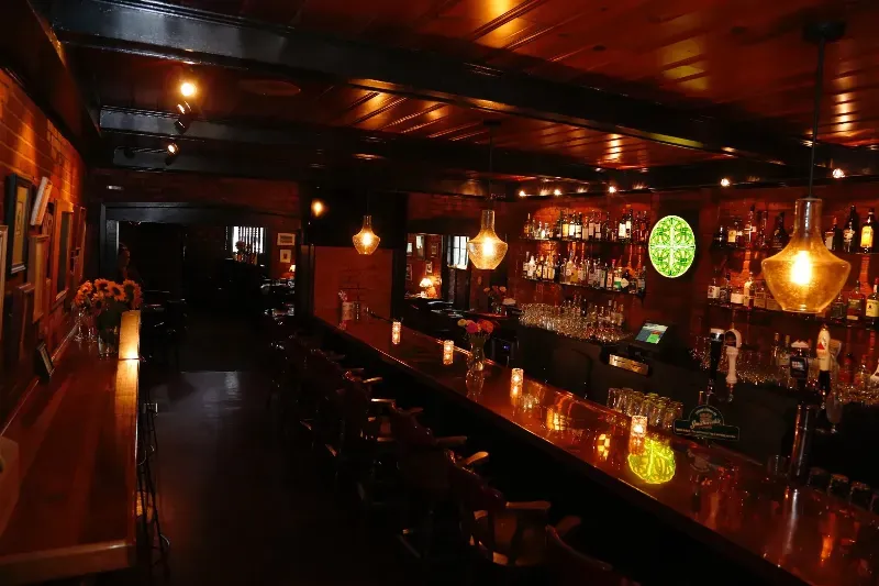 A bar with a long bar and a lot of bottles on the shelf.
