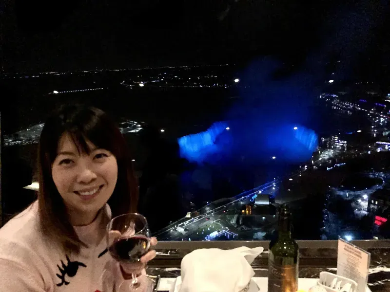 A woman is sitting at a table holding a glass of wine