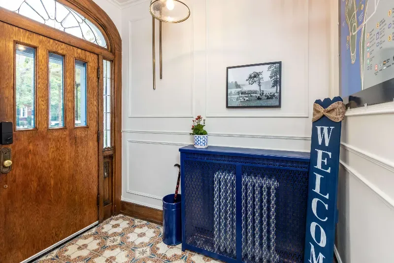 A hallway with a wooden door and a blue welcome sign.