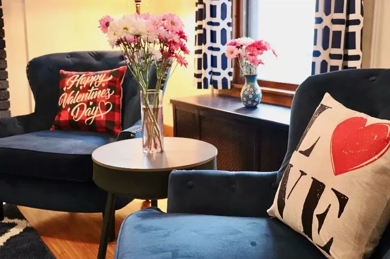 A living room with two chairs and a table with a pillow that says happy valentine 's day.