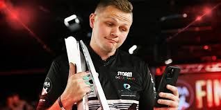 Three women look at a smartphone, smiling. One wears pink headphones, others athletic wear, outdoors.