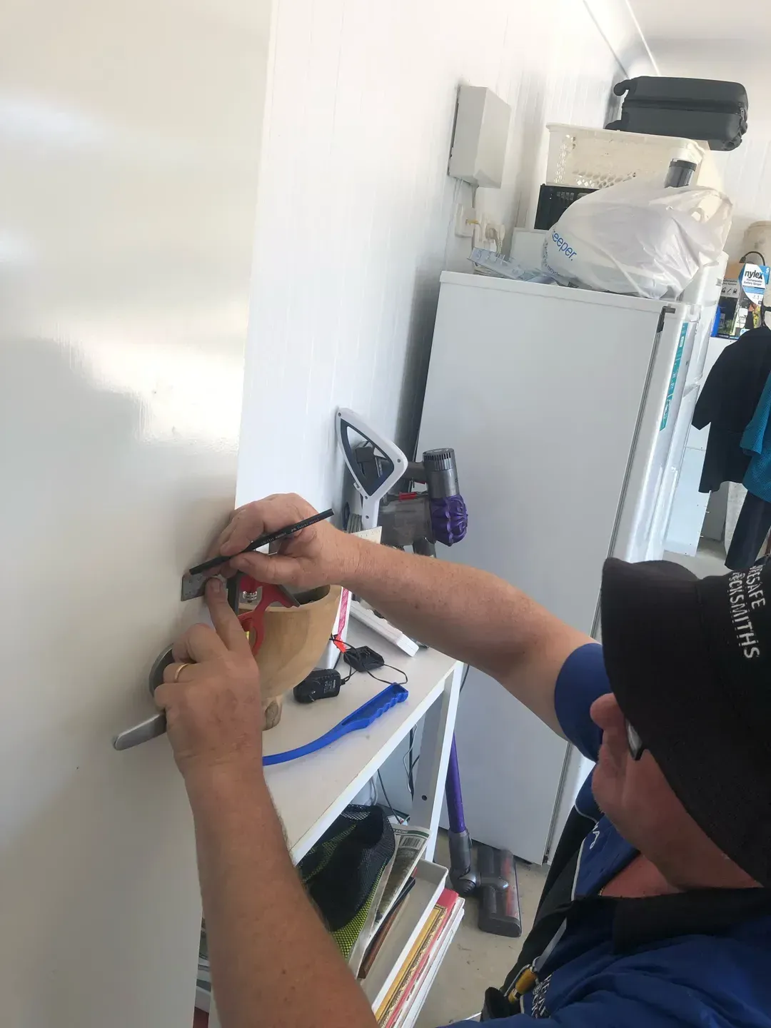 Person in Blue Shirt Installing Something on A White Wall — Suresafe Locksmiths in Glenvale, QLD