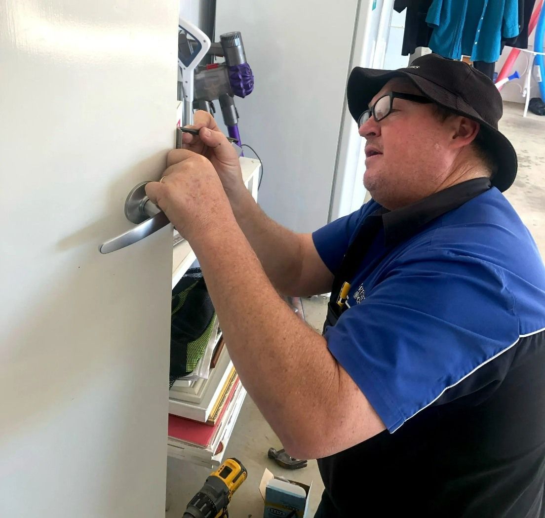 A Man Wearing a Hat and Glasses is Working on a Door — Suresafe Locksmiths in Glenvale, QLD