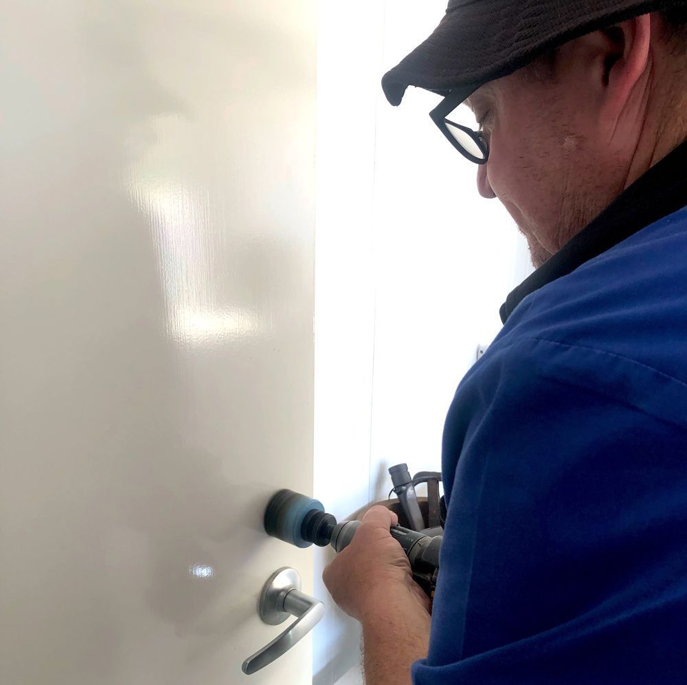 A Man in a Shirt is Fixing a Door — Suresafe Locksmiths in Glenvale, QLD