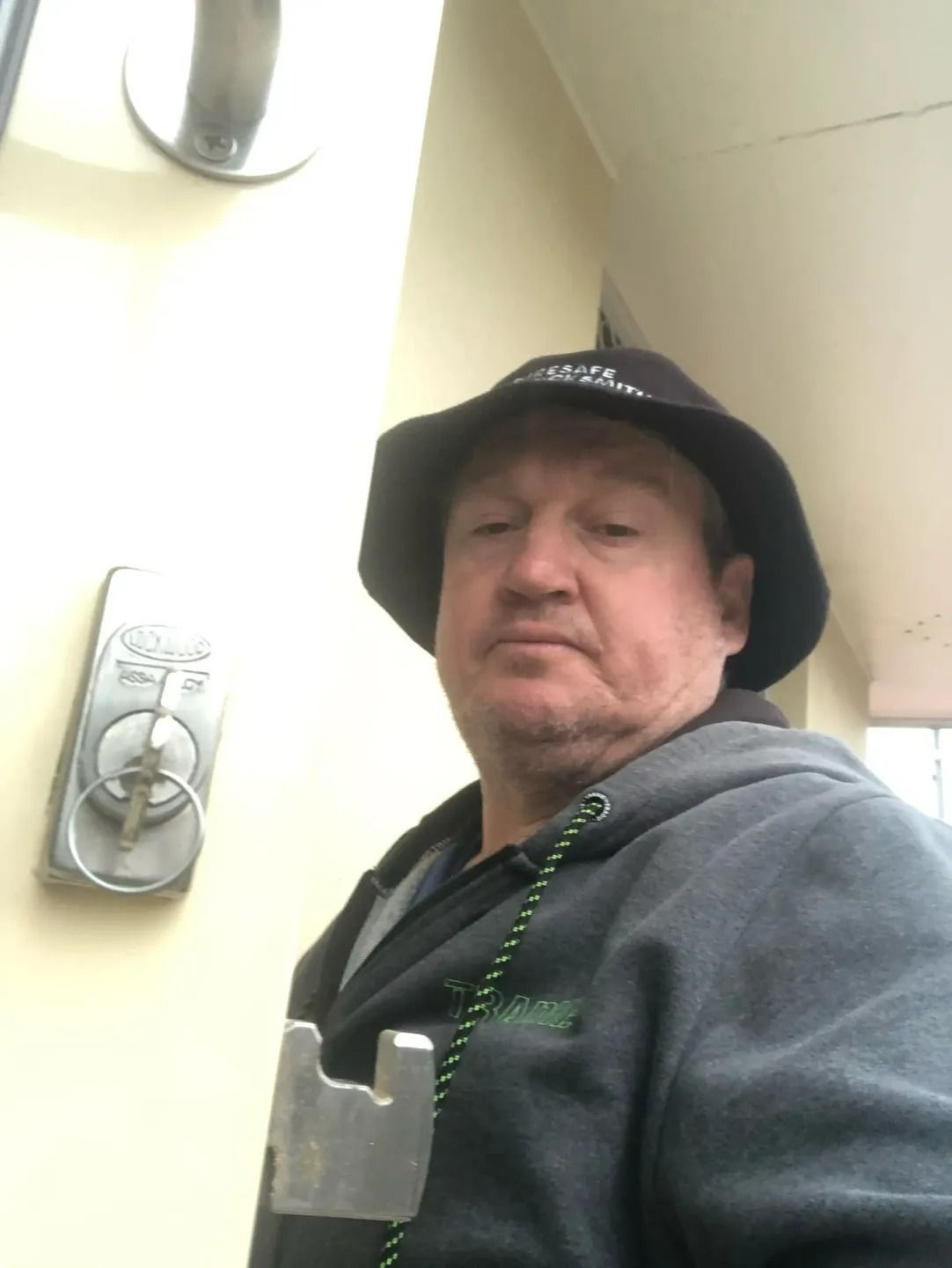 A Man Wearing a Hat is Standing in Front of a Door — Suresafe Locksmiths in Glenvale, QLD