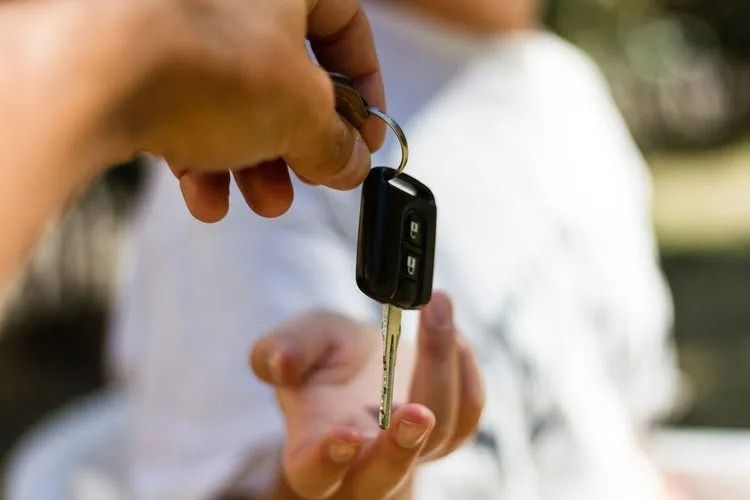 A Person is Handing a Car Key to Another Person — Suresafe Locksmiths in Glenvale, QLD