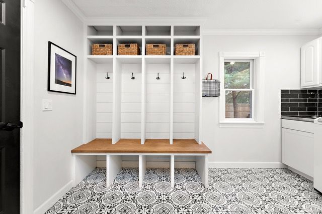 White entryway with storage lockers, bench, patterned floor, and a framed picture.
