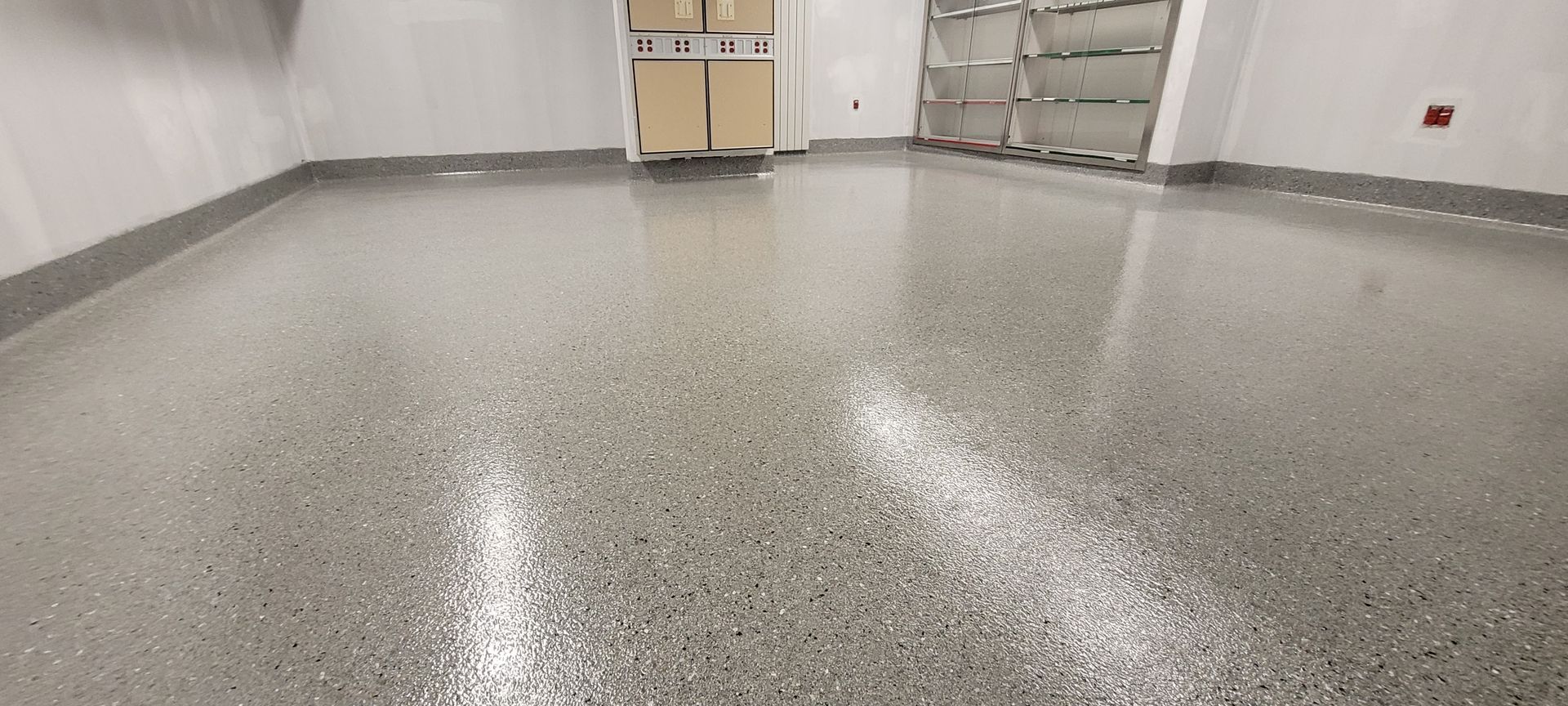 Une pièce avec un sol en béton brillant et une porte.