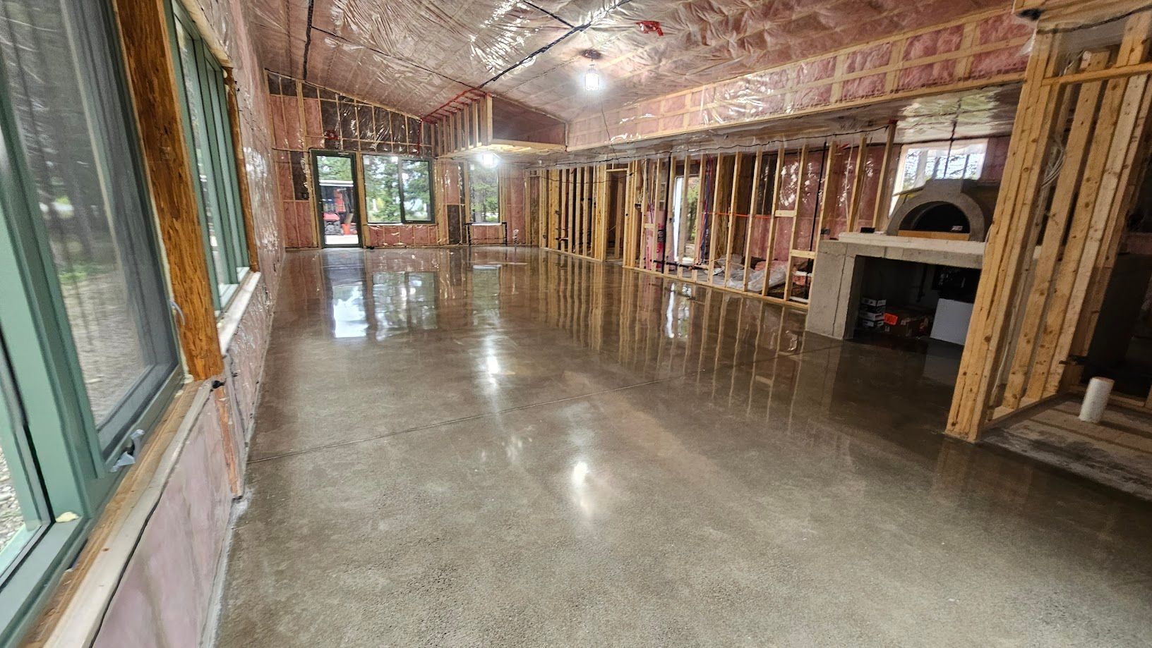 Une grande pièce avec un sol en béton et beaucoup de fenêtres.