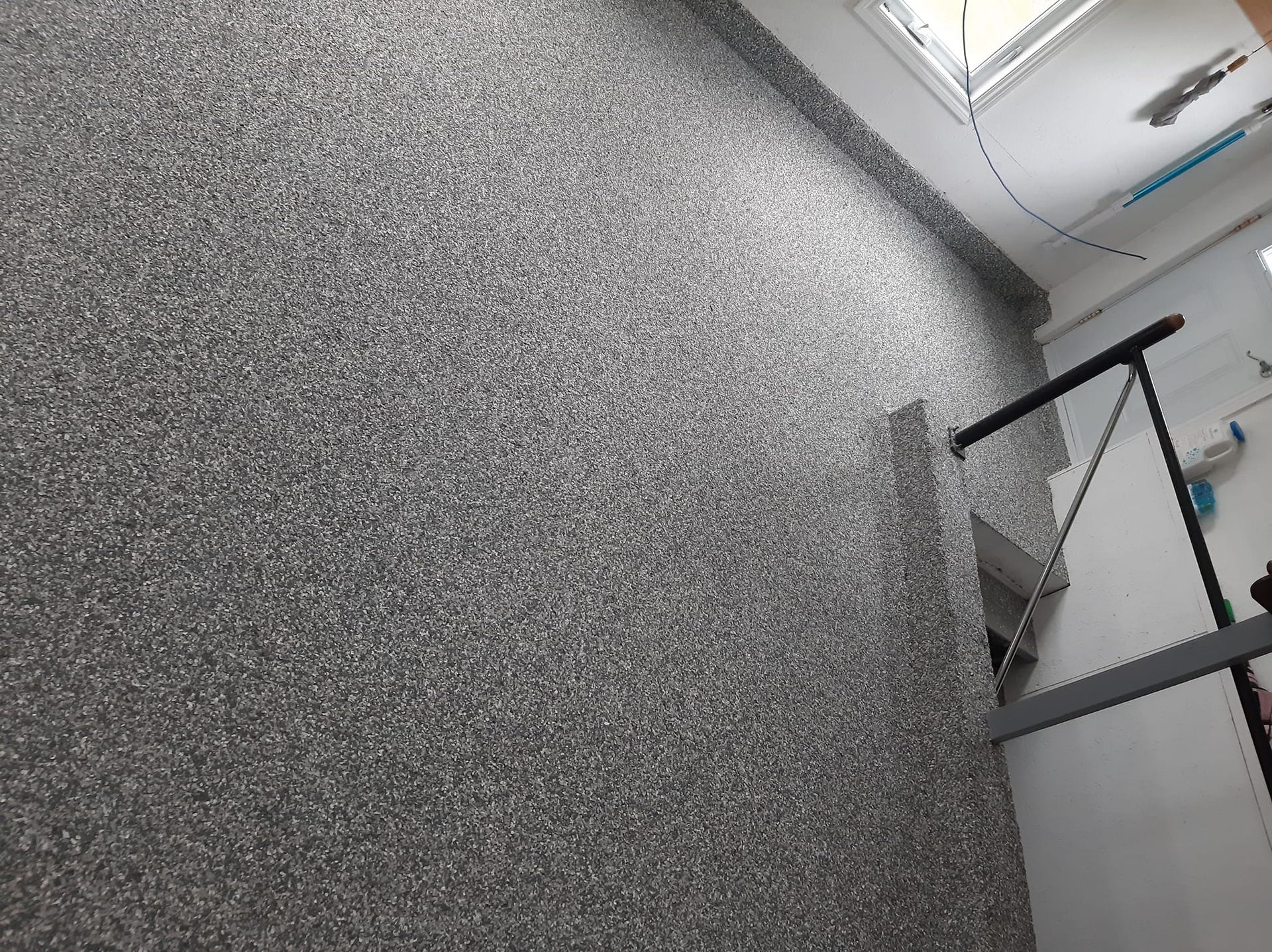 Un escalier avec un mur gris et une rampe noire.