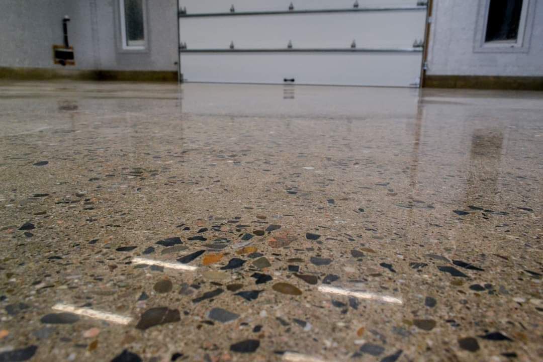 Un sol en béton brillant dans un garage avec une porte de garage en arrière-plan.