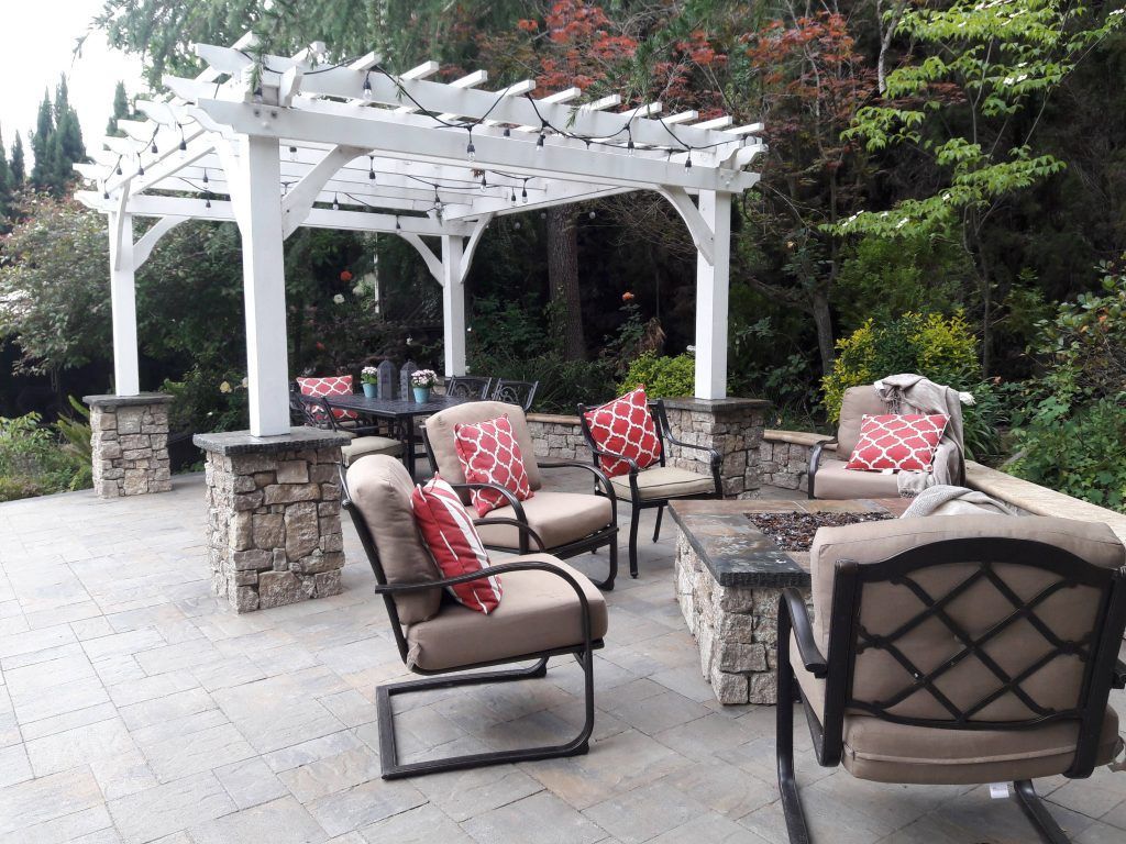 A patio with chairs and a fire pit under a pergola