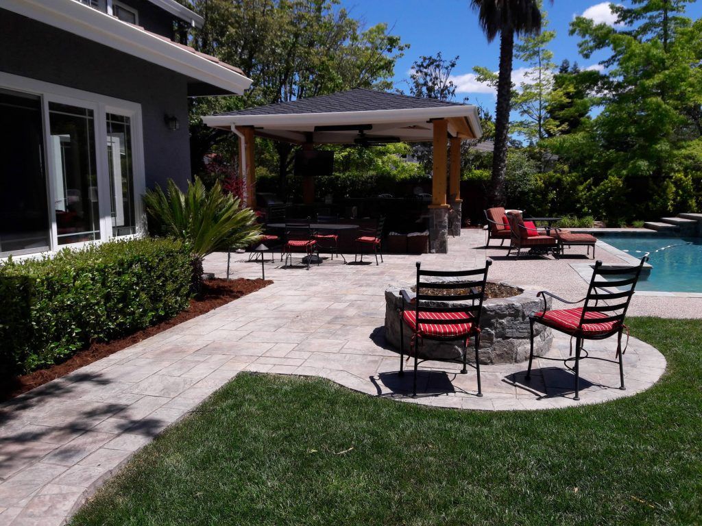 A patio with a fire pit and chairs next to a pool