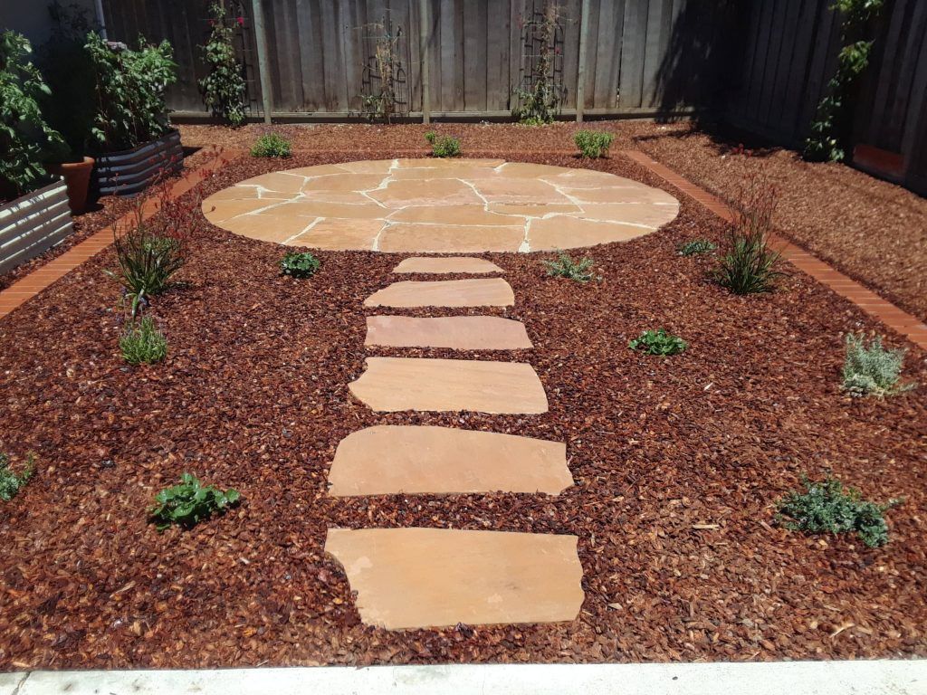 A garden with a stone walkway leading to a circular area