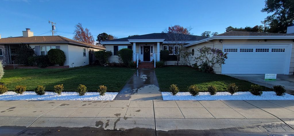 A house with a lush green lawn and a white driveway