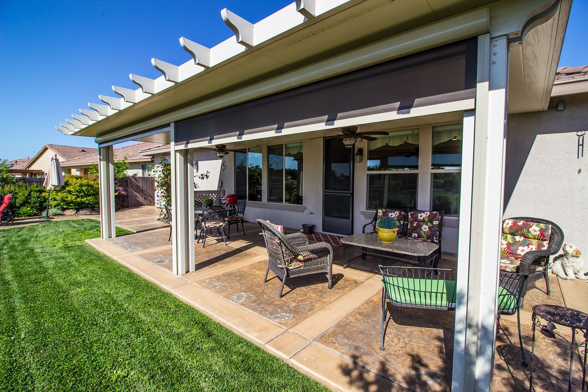 There is a patio with a pergola and a lot of furniture on it.