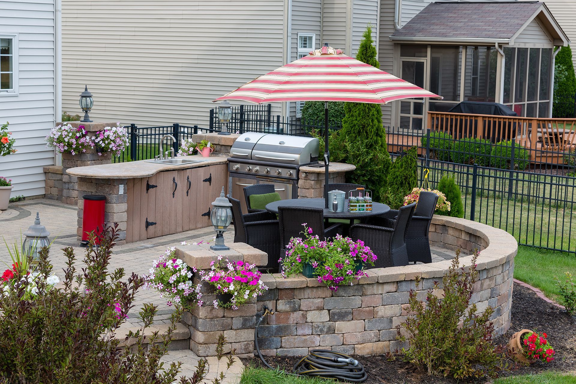 A patio with a grill , table and chairs and an umbrella.