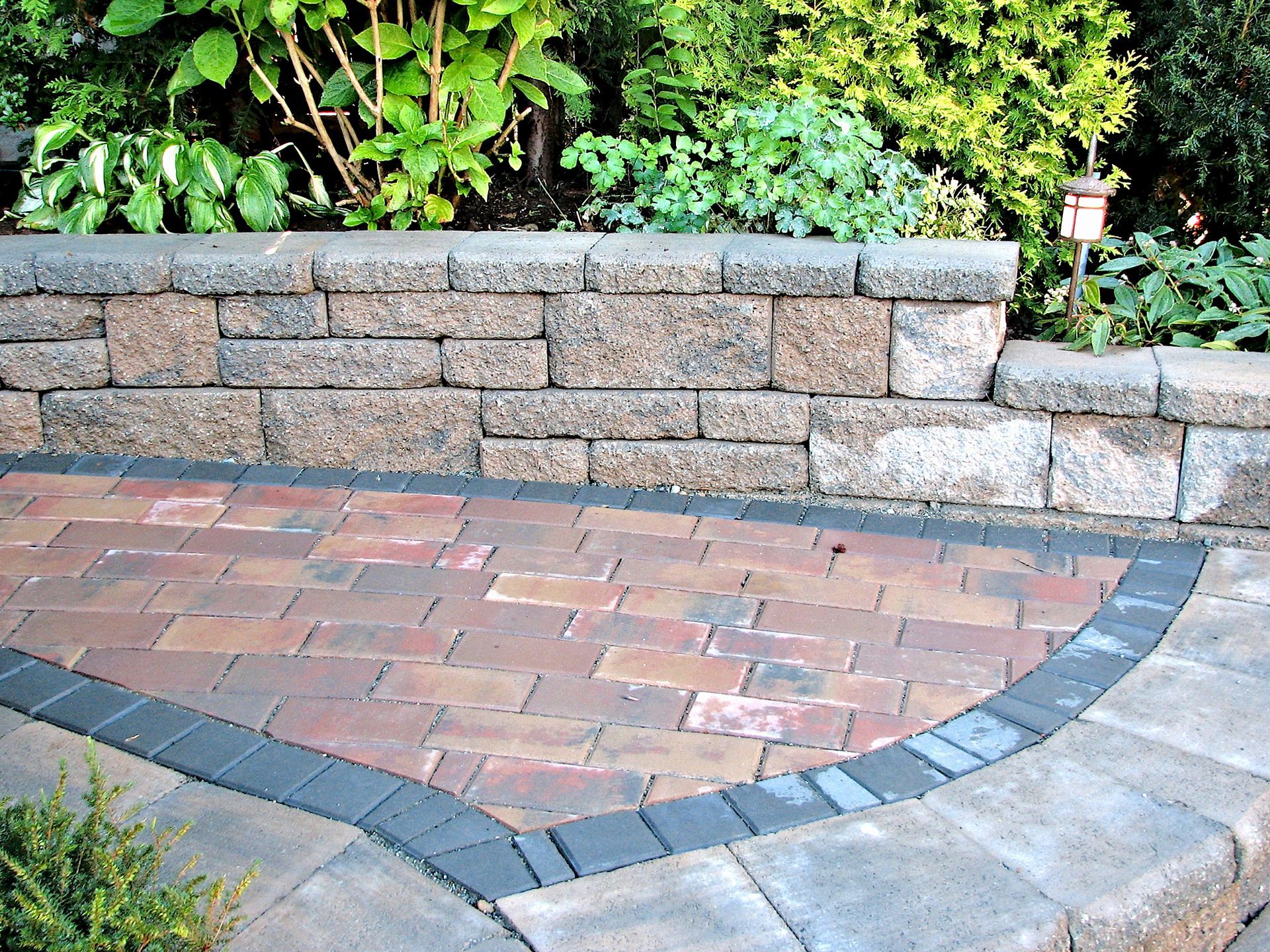 A brick walkway with a stone wall in the background