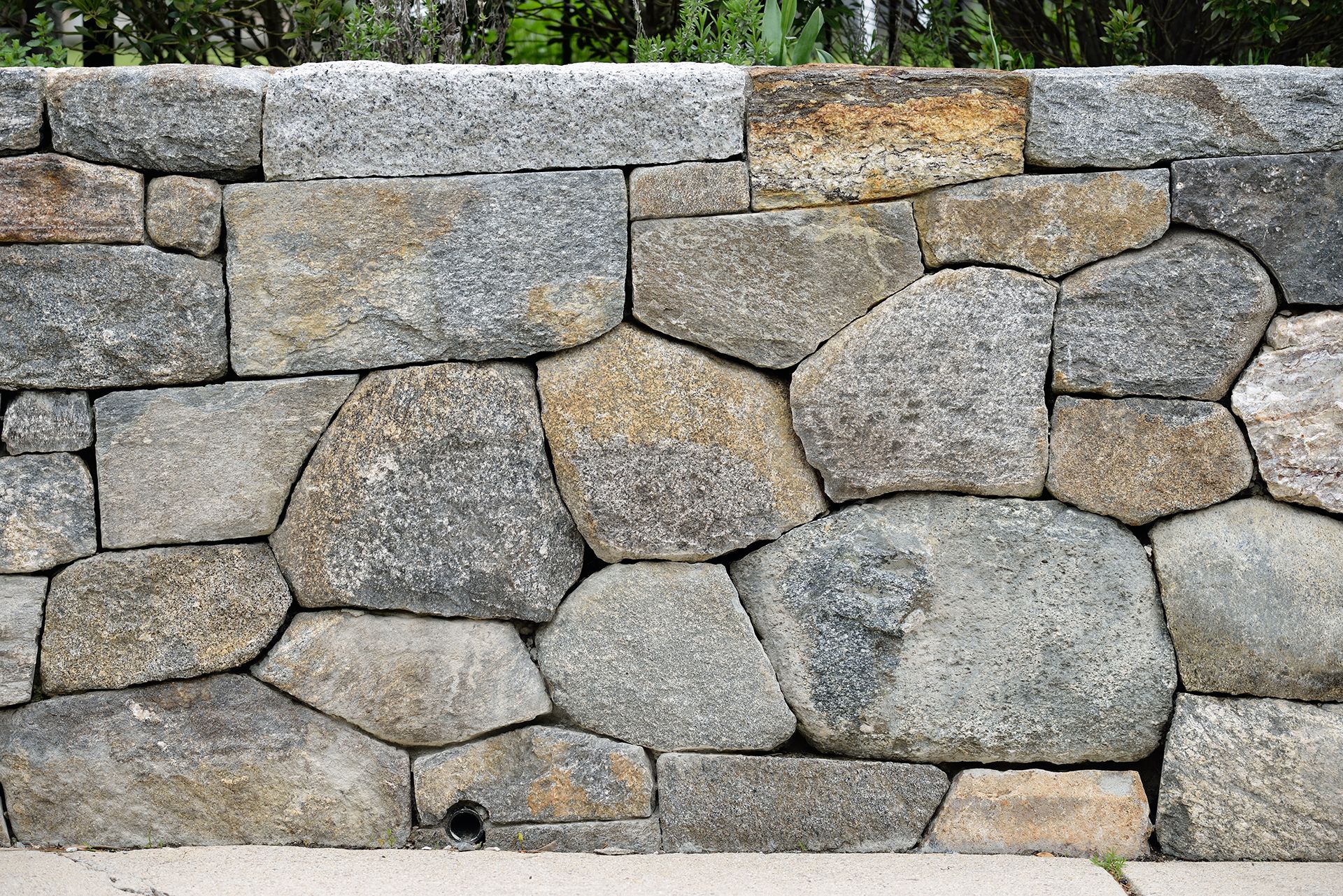 A close up of a stone wall with trees in the background.