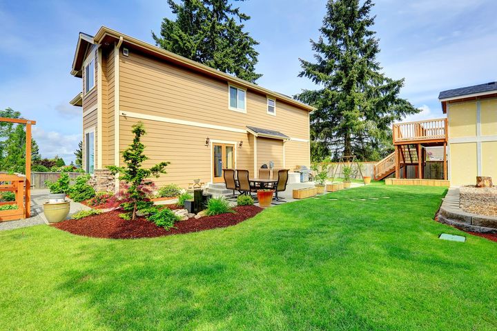 A house with a large lush green lawn in front of it.