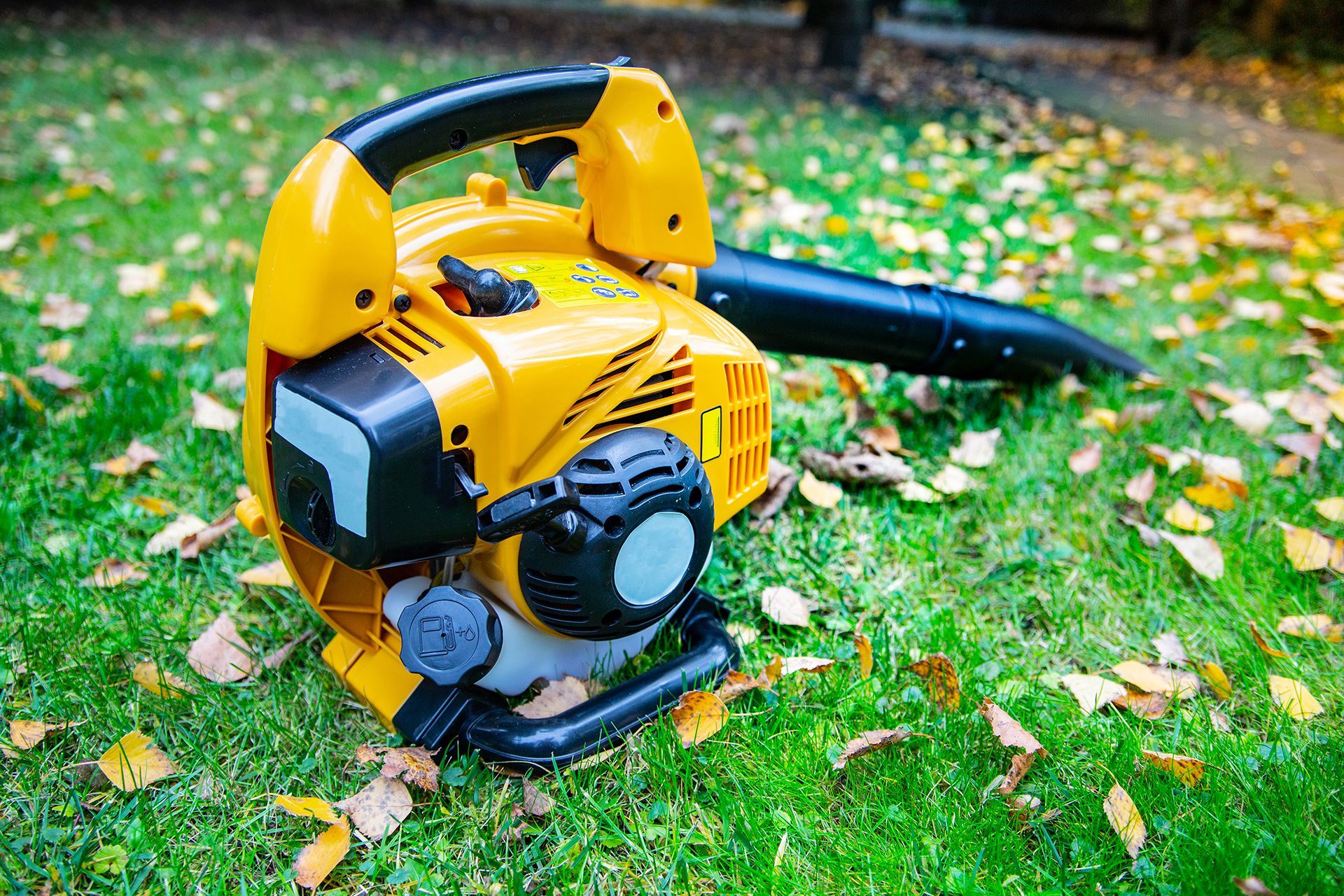A yellow leaf blower is sitting on top of a lush green lawn.