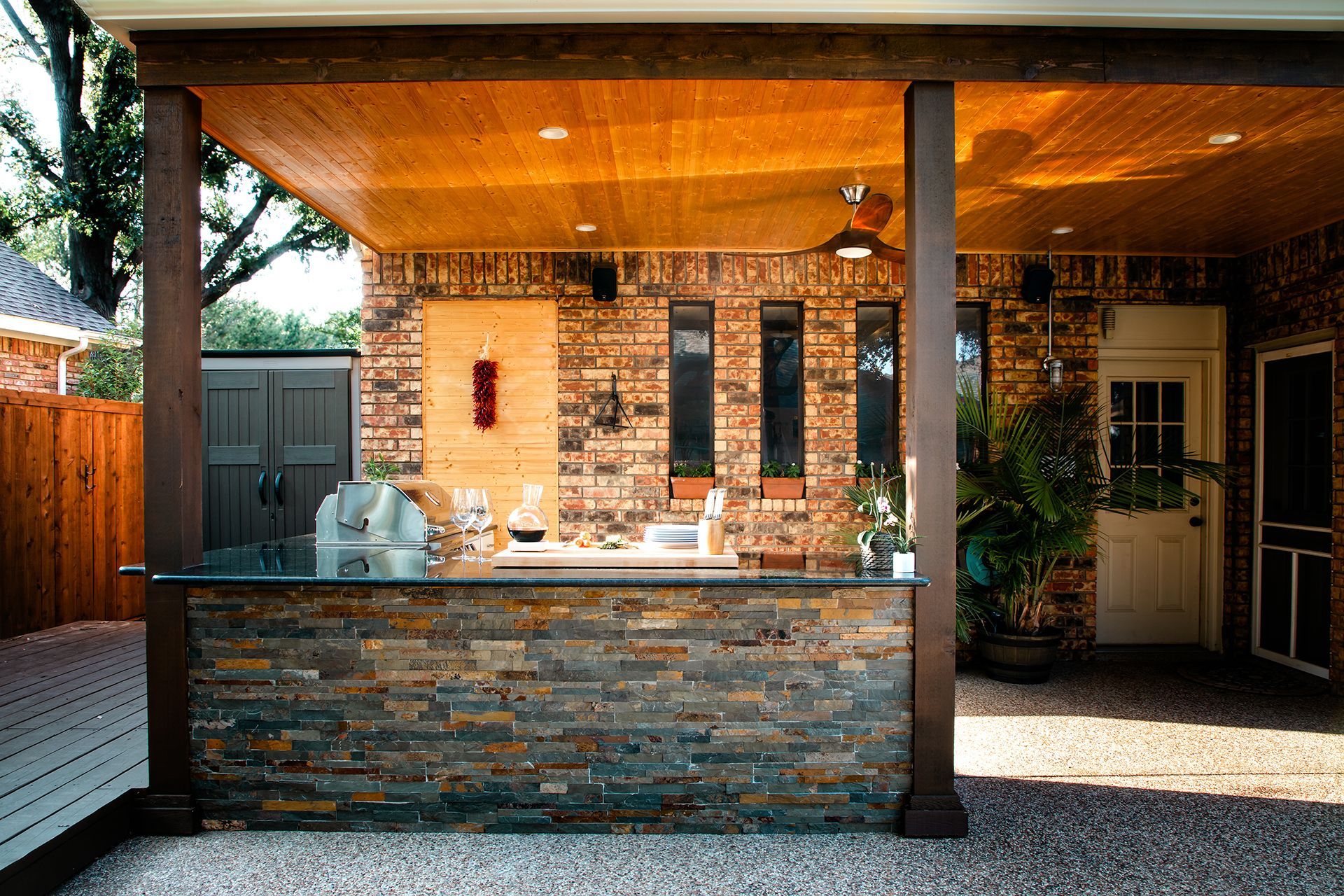 An outdoor kitchen with a brick wall and a wooden ceiling