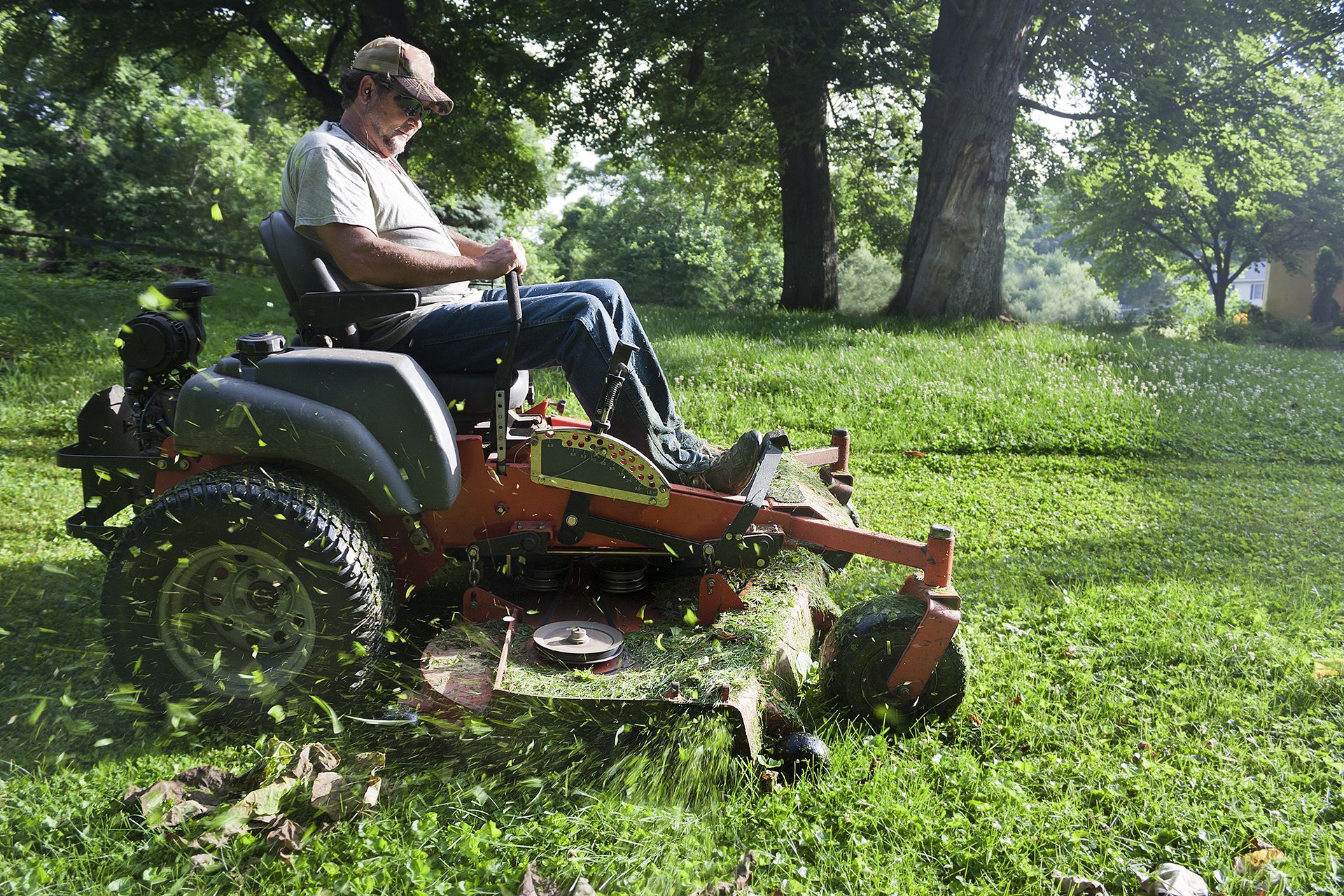 A man is sitting on a lawn mower cutting grass.