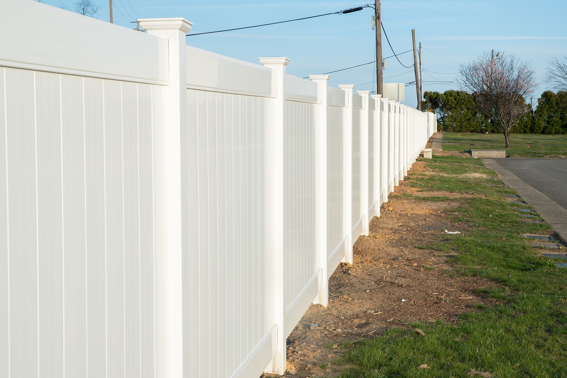 A white vinyl fence is sitting next to a road.