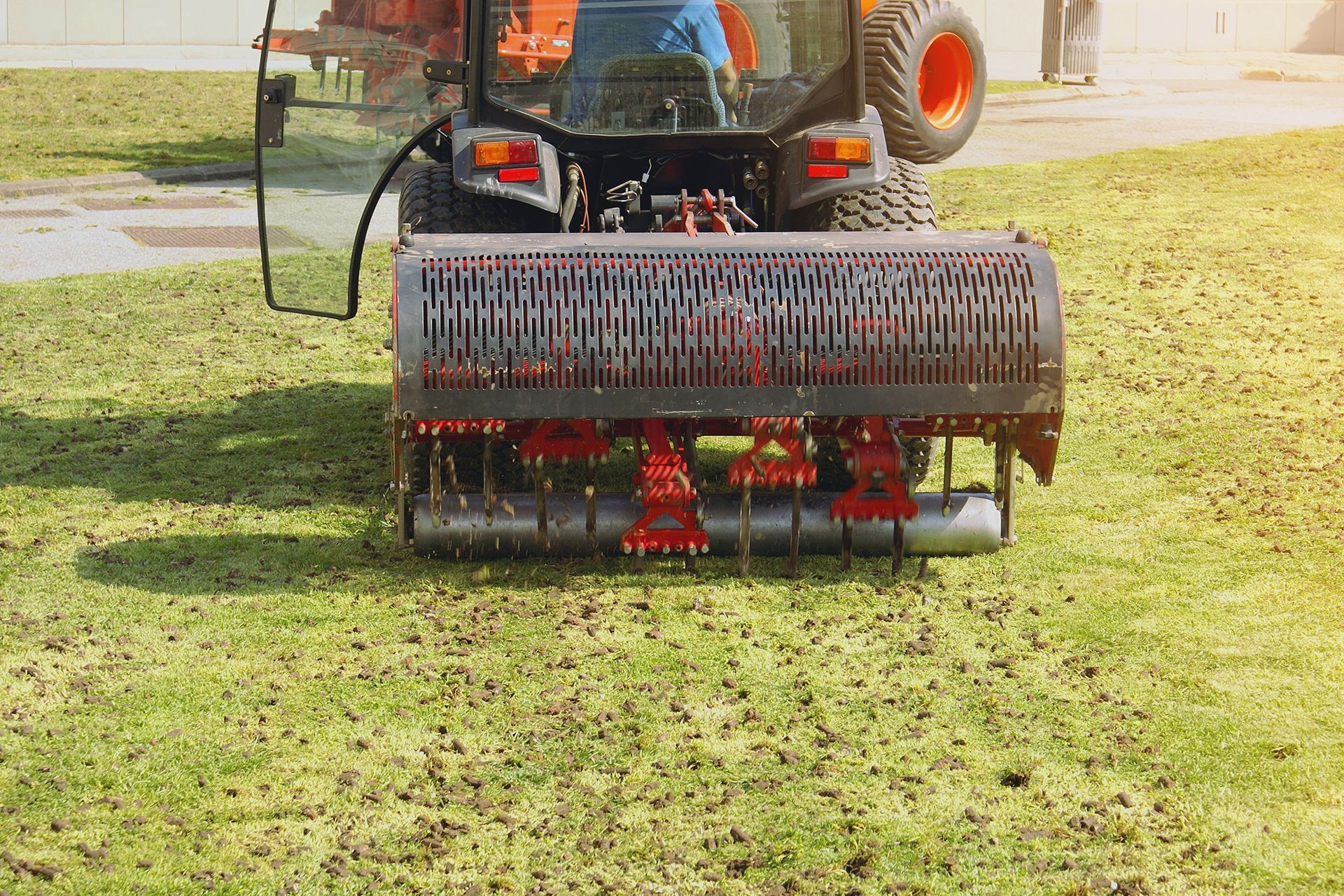 A tractor is spreading fertilizer on a lush green lawn.