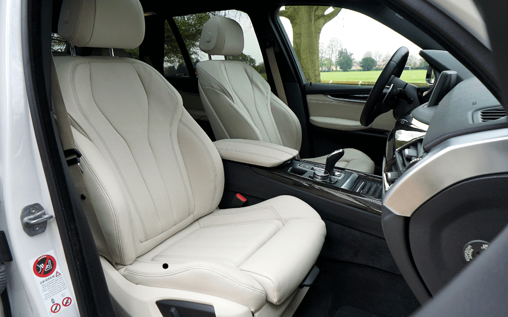 a mechanic doing a pre-purchase inspection on a white car with white interior seats