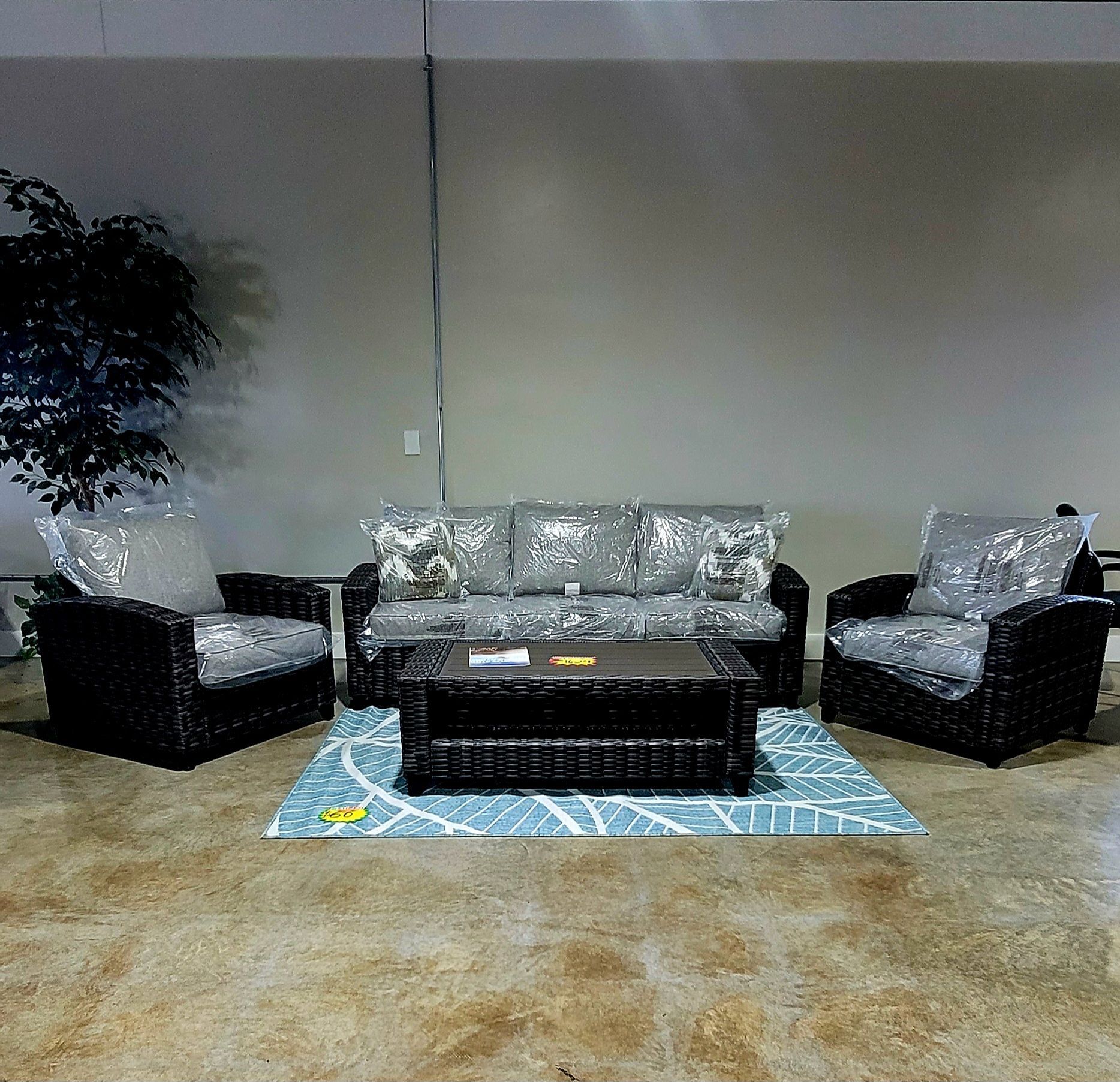 Living room with black wicker sofa and chairs around a dark coffee table on a blue rug