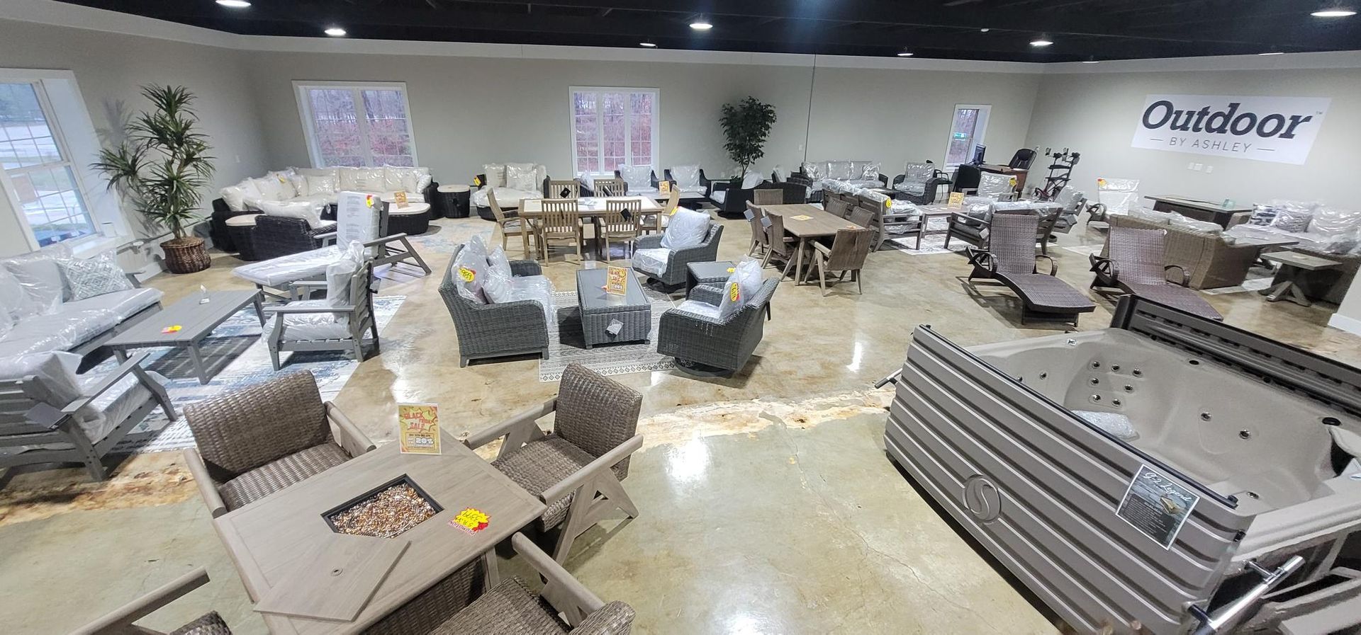 Outdoor furniture showroom with gray patio sets and tables displayed in a bright store interior