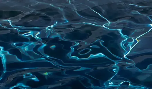 Blue water surface with shimmering light ripples and reflections
