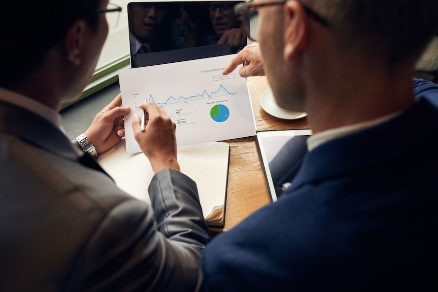 Two professionals review a printed analytics report with charts and graphs.