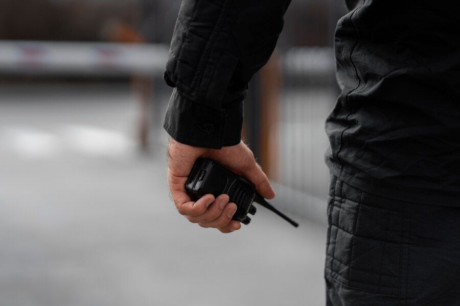 Security guard holding radio in hand, ready for event security or executive protection.