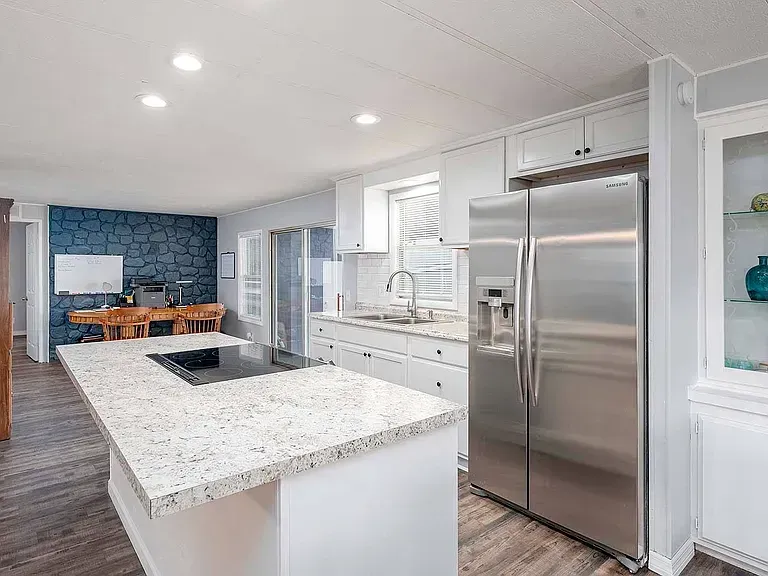 Bright kitchen with a white island, stainless steel refrigerator, and blue accent wall.