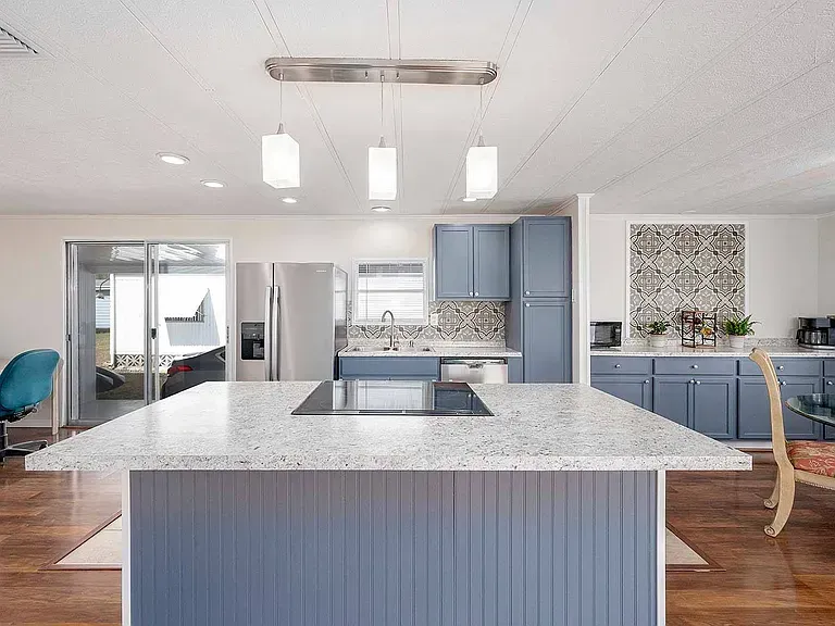 Modern kitchen with blue cabinets, large island, and pendant lights.