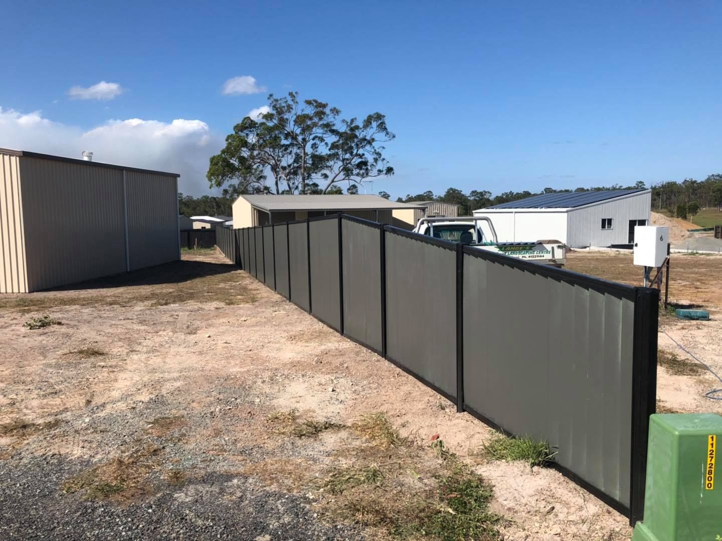 Long Fence Surrounds a Dirt Field With a Shed in the Background — Lange's Fencing and Landscaping Centre in Island Plantation, QLD