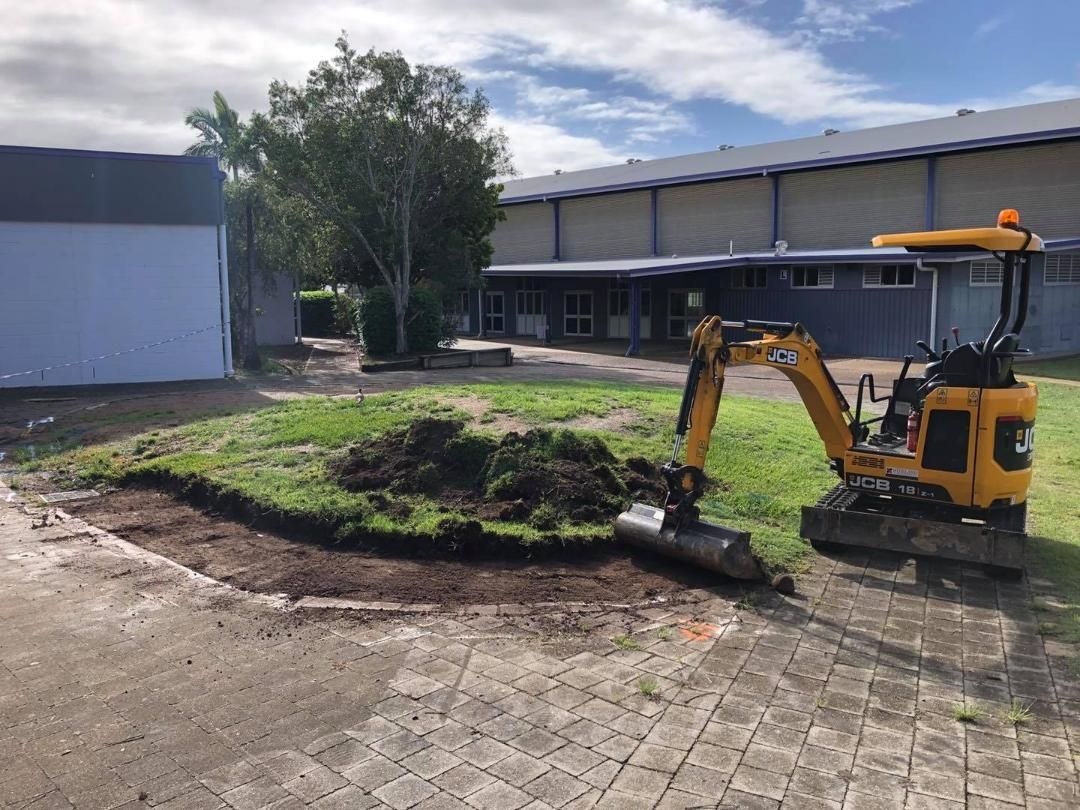 Small Yellow Excavator is Digging a Hole in the Ground in Front of a Building — Lange's Fencing and Landscaping Centre in Gympie, QLD