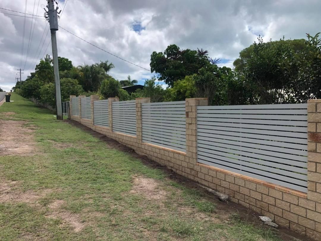 Fence Made of Bricks and Aluminum is Surrounding a Grassy Field — Lange's Fencing and Landscaping Centre in Maryborough, QLD