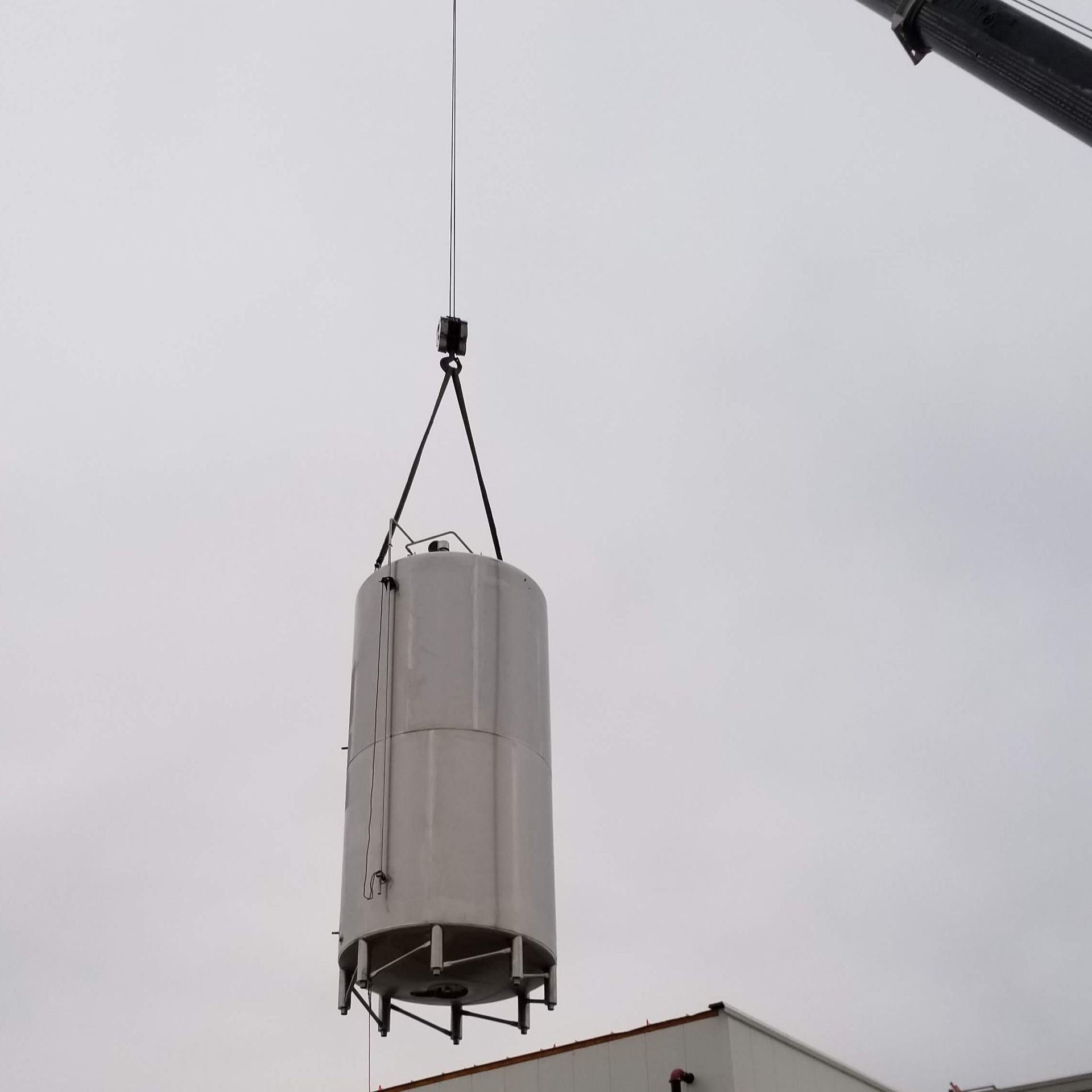 A large white cylinder is being lifted by a crane