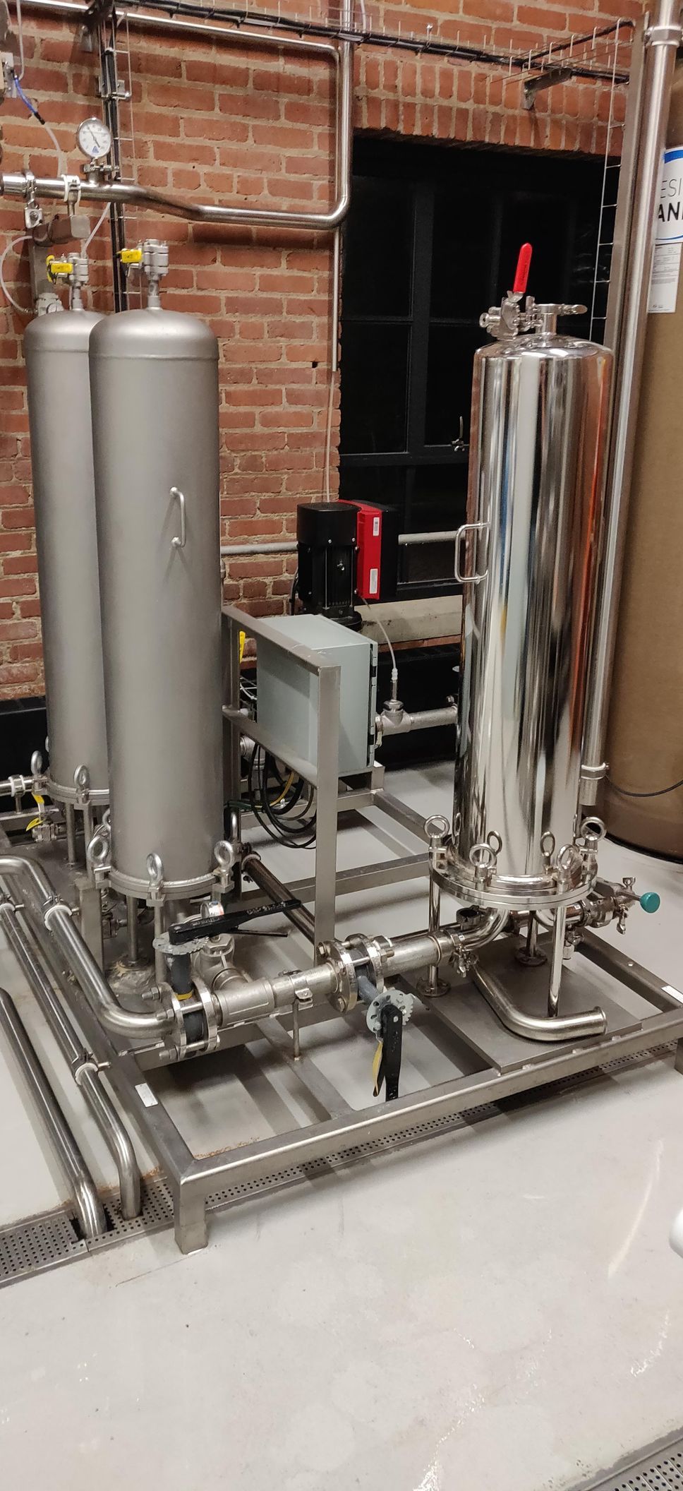 A stainless steel machine is sitting in a room next to a brick wall.