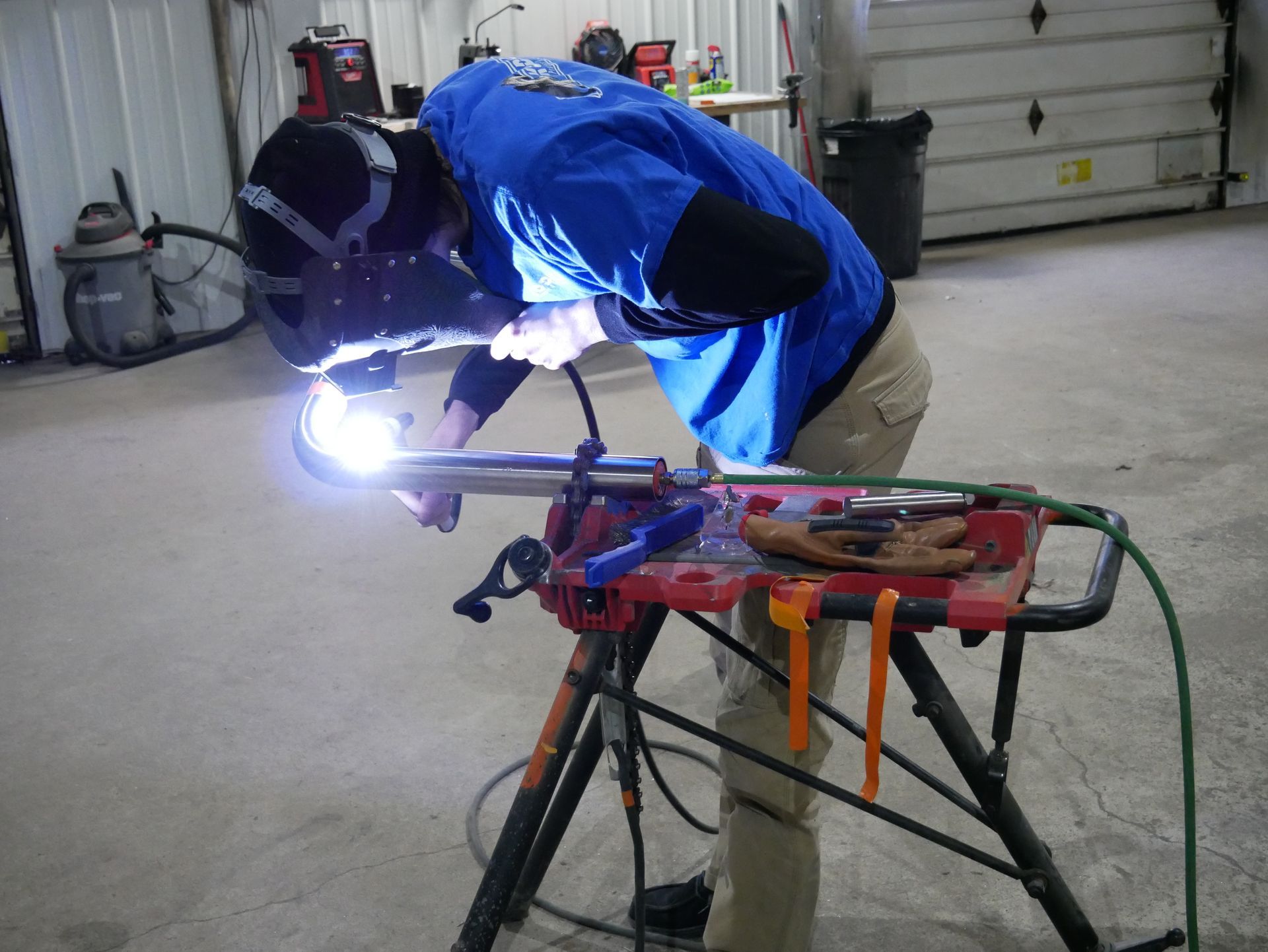 A man in a blue shirt is welding a piece of metal