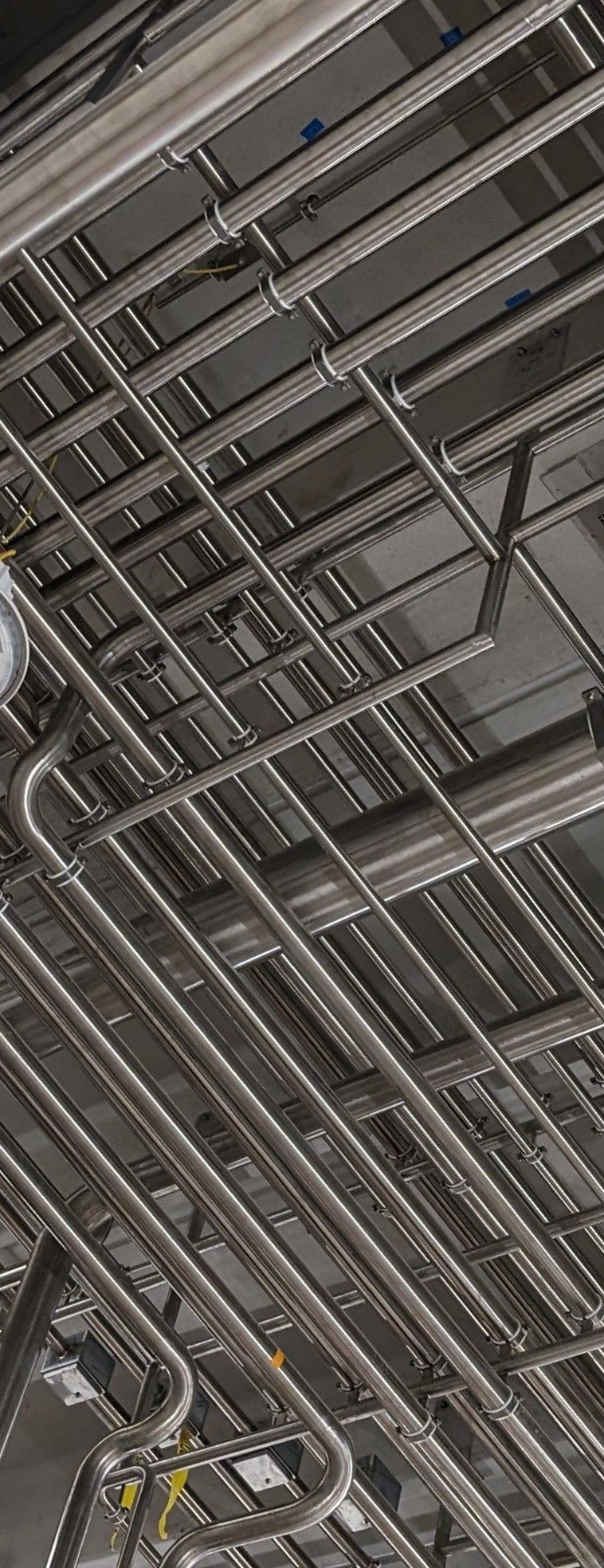 A bunch of pipes are hanging from the ceiling of a building.