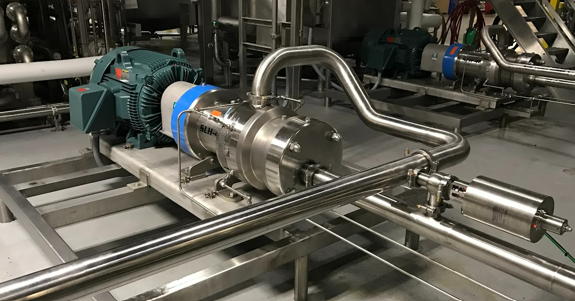 A stainless steel pump is sitting on top of a table in a factory.