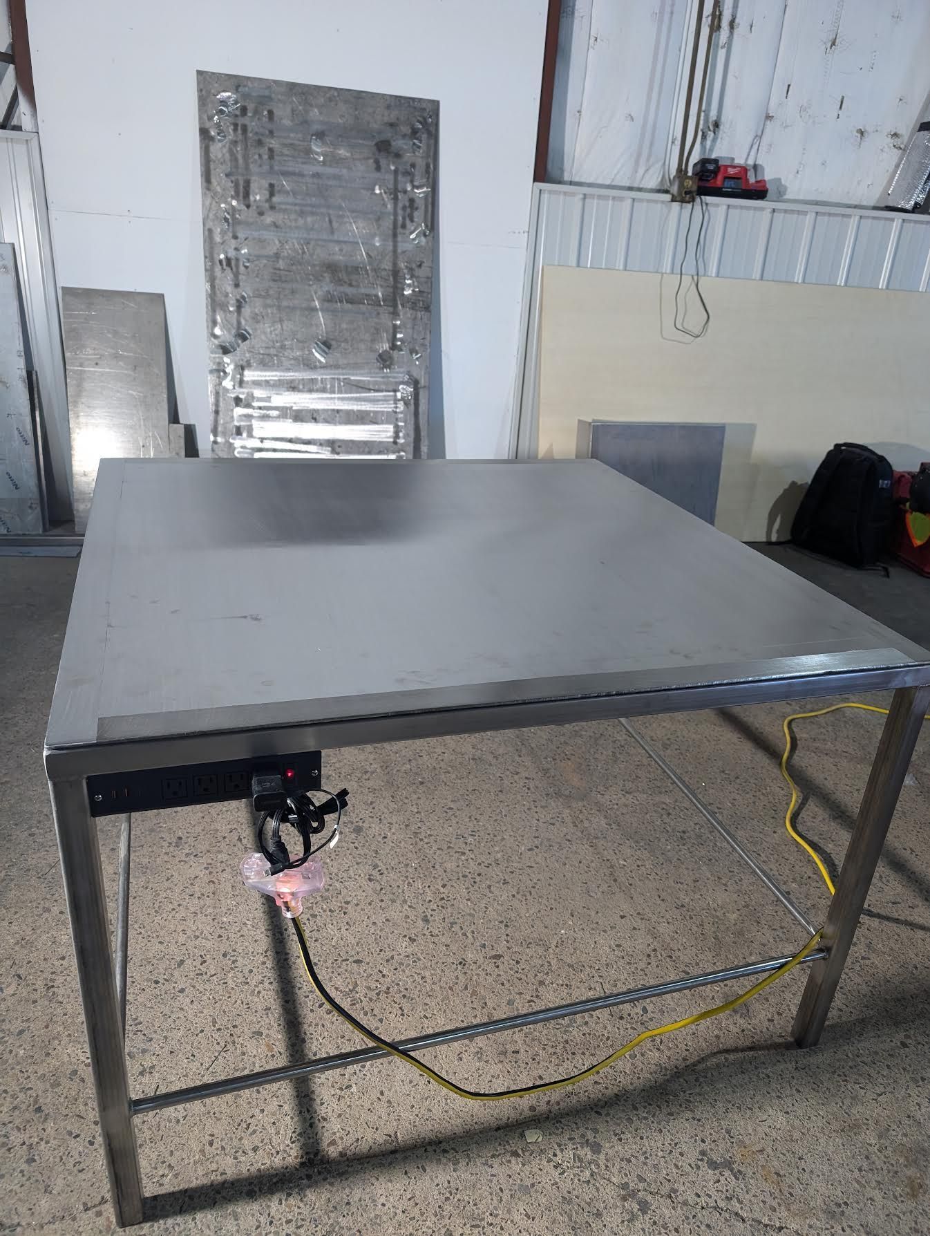 A stainless steel table is sitting on a tiled floor in a room.