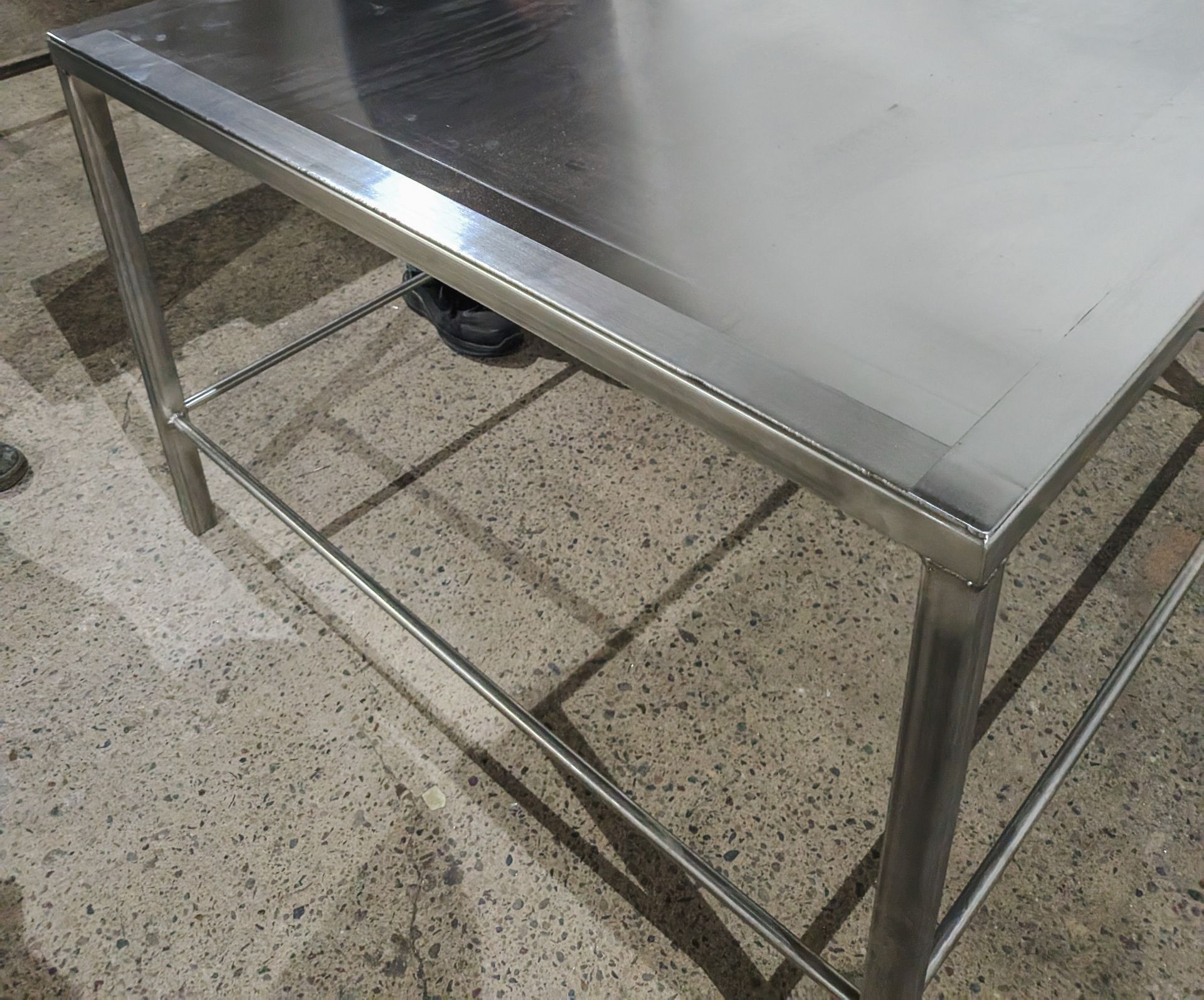 A stainless steel table is sitting on a tiled floor.
