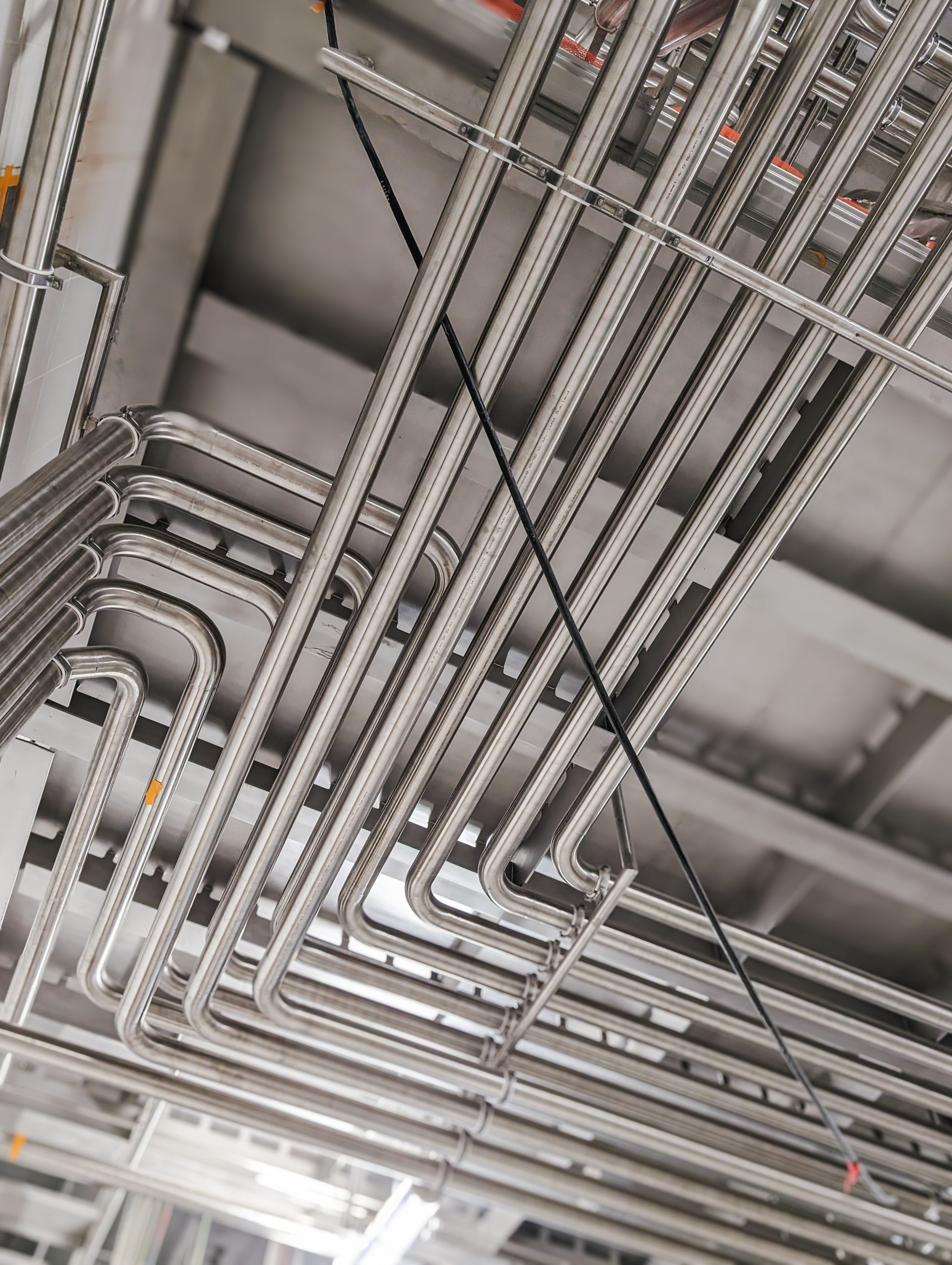 A bunch of stainless steel pipes are hanging from the ceiling of a building.