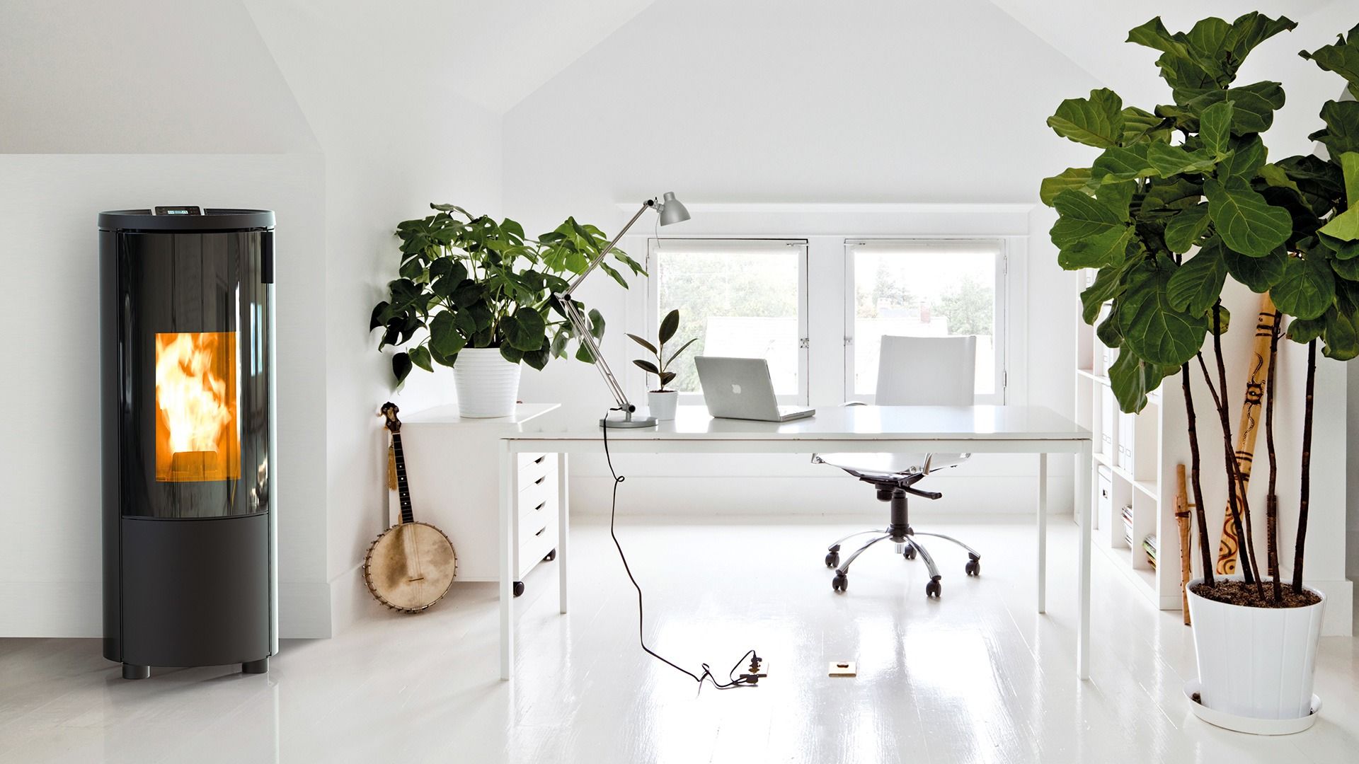 Stufa a pellet nera in un ufficio bianco e luminoso con piante e scrivania.