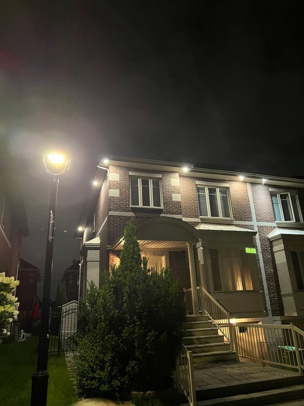 Une maison est éclairée la nuit avec un lampadaire devant elle.